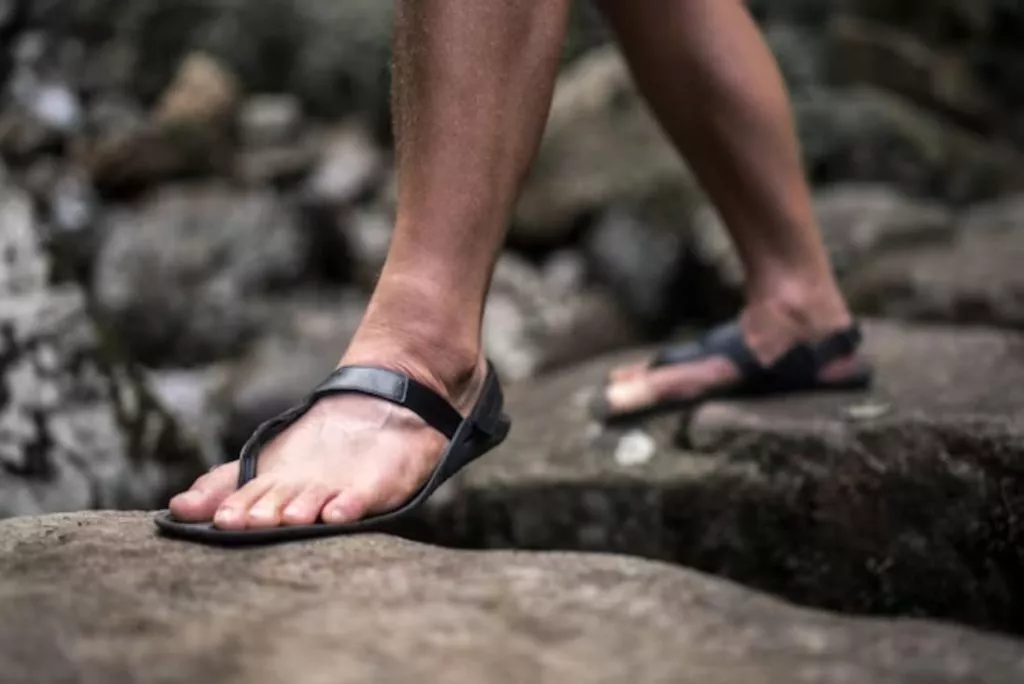 man feet in barefoot sandals walking on stones